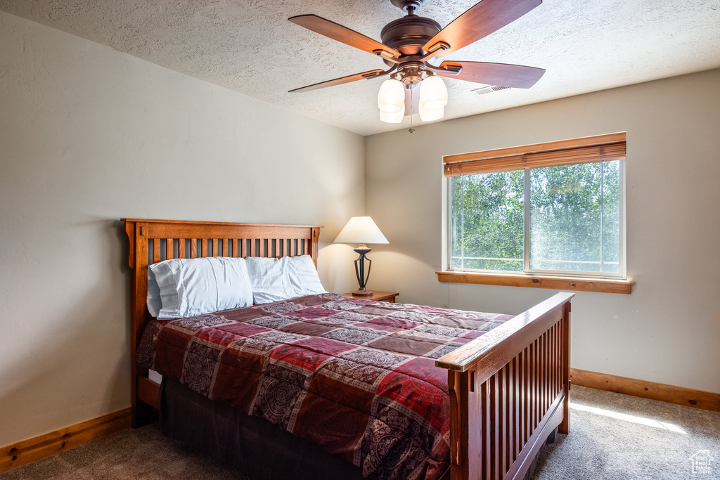 Bedroom with carpet floors, a textured ceiling, and ceiling fan