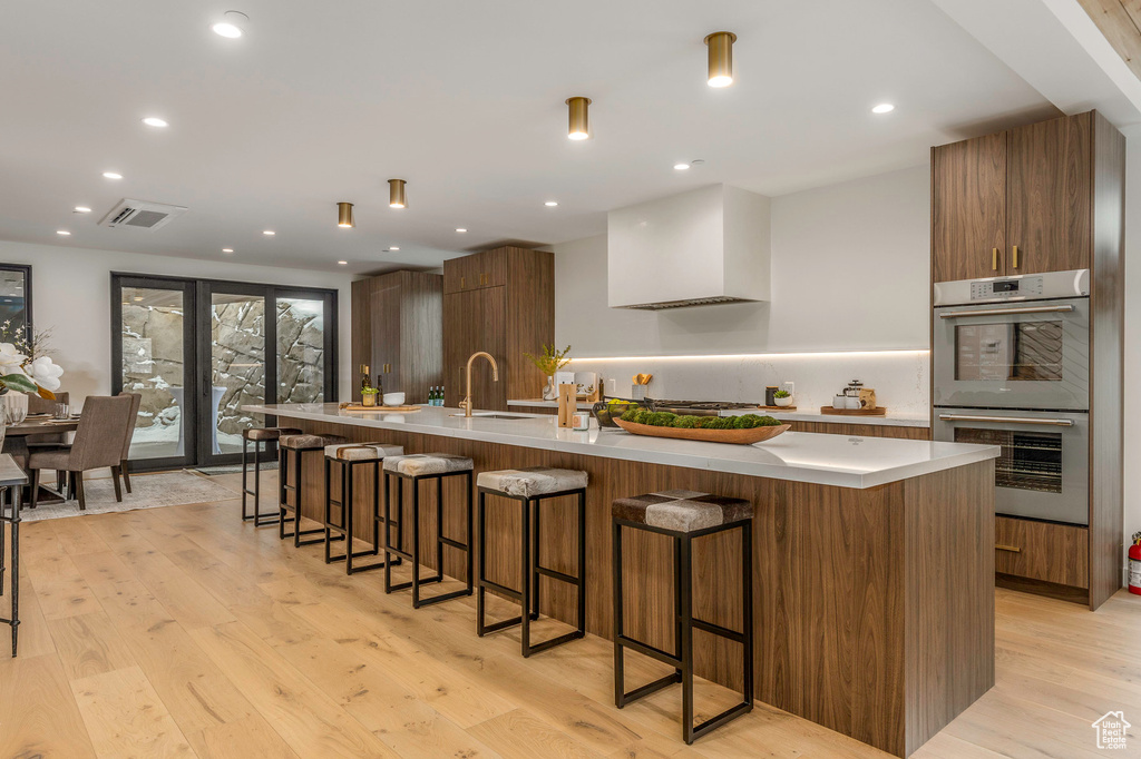 Kitchen featuring light wood-style floors, modern cabinets, visible vents, a sink, and stainless steel double oven