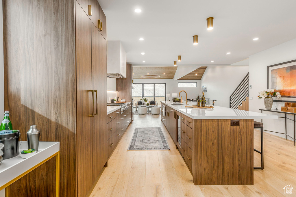 Kitchen featuring light countertops, light wood finished floors, a breakfast bar area, and modern cabinets