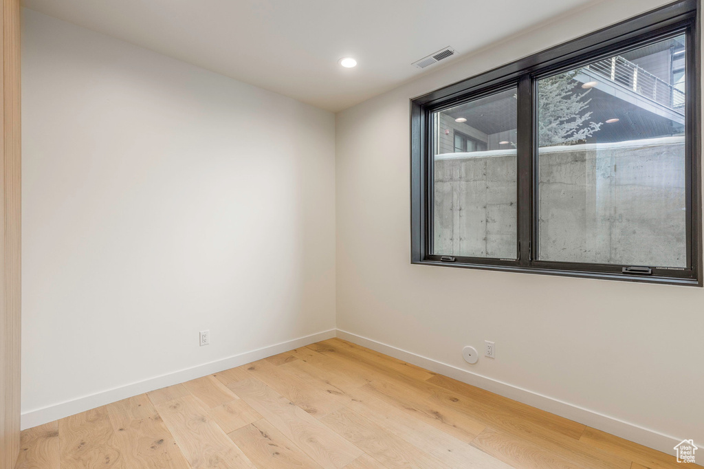 Empty room featuring visible vents, baseboards, light wood-type flooring, and recessed lighting