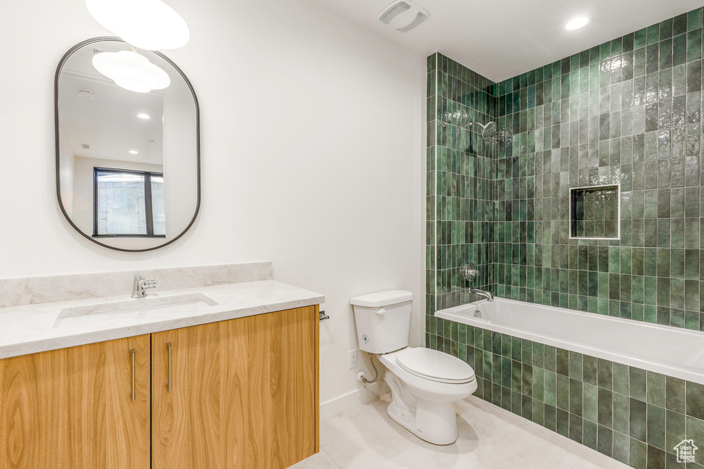Bathroom featuring vanity, tile patterned flooring, toilet, tiled shower / bath, and baseboards