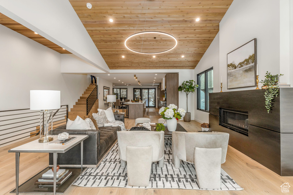 Living area with wooden ceiling, wood finished floors, a glass covered fireplace, and stairway