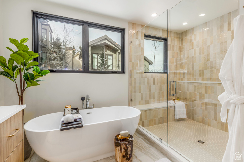 Bathroom with a shower stall, a freestanding bath, and a healthy amount of sunlight