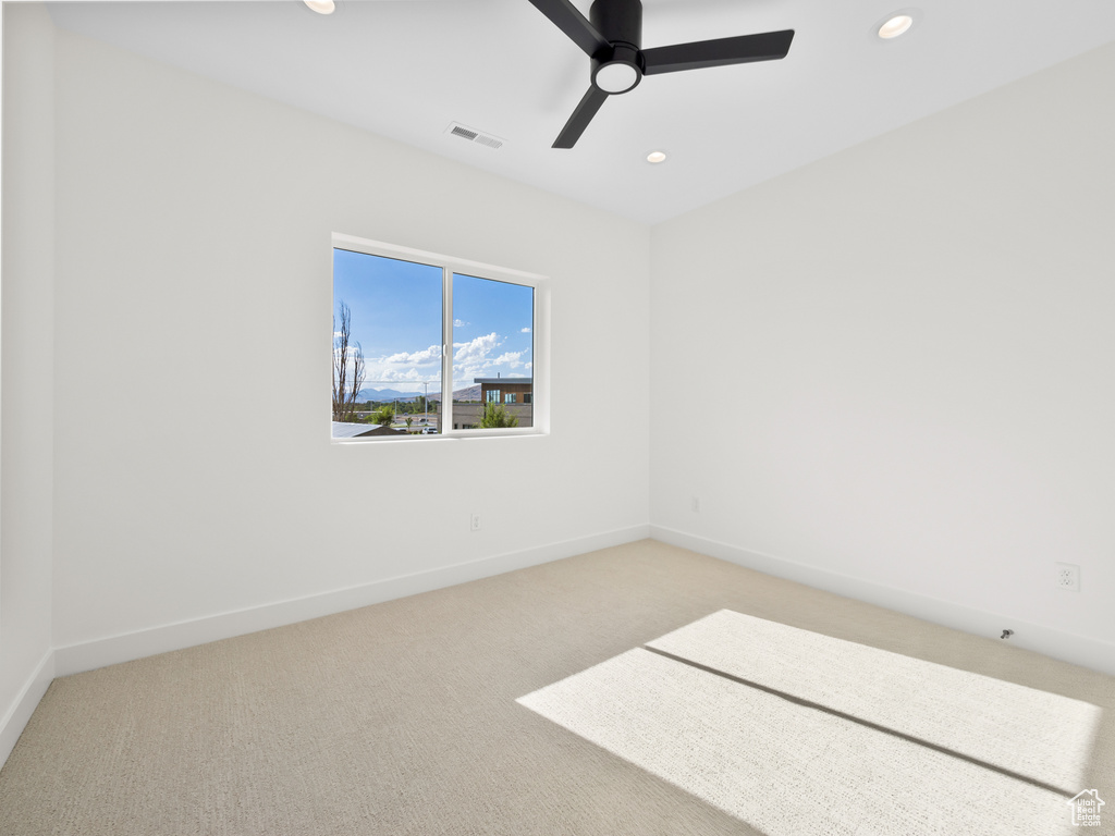 Carpeted spare room featuring ceiling fan