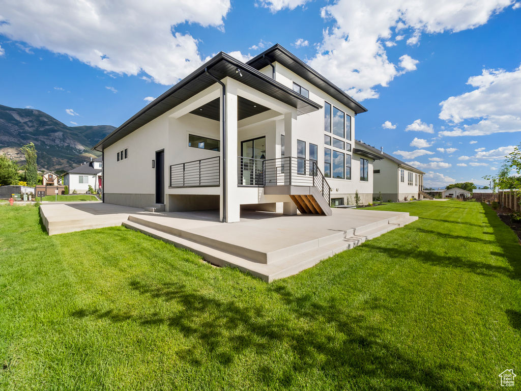 Back of house with a mountain view, a patio area, and a yard