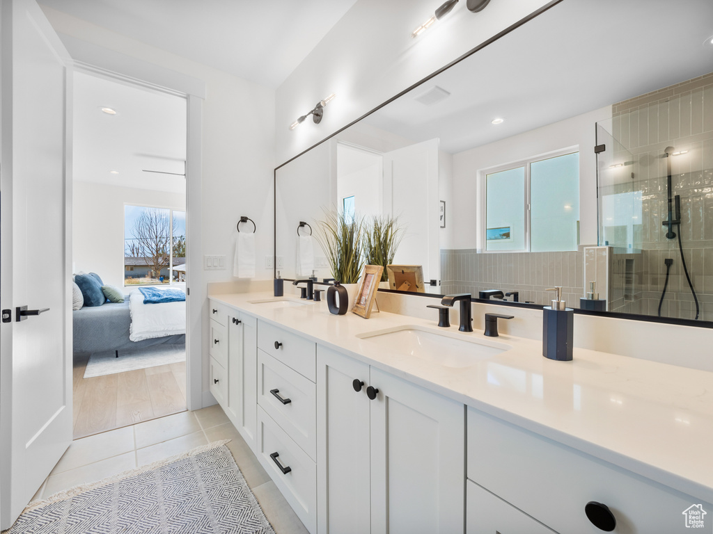 Bathroom with tile patterned flooring, a tile shower, and double sink vanity