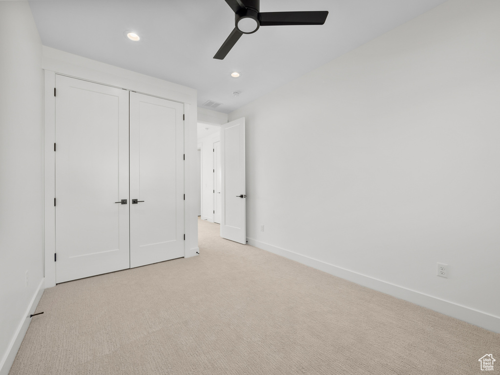 Unfurnished bedroom with a closet, ceiling fan, and light carpet