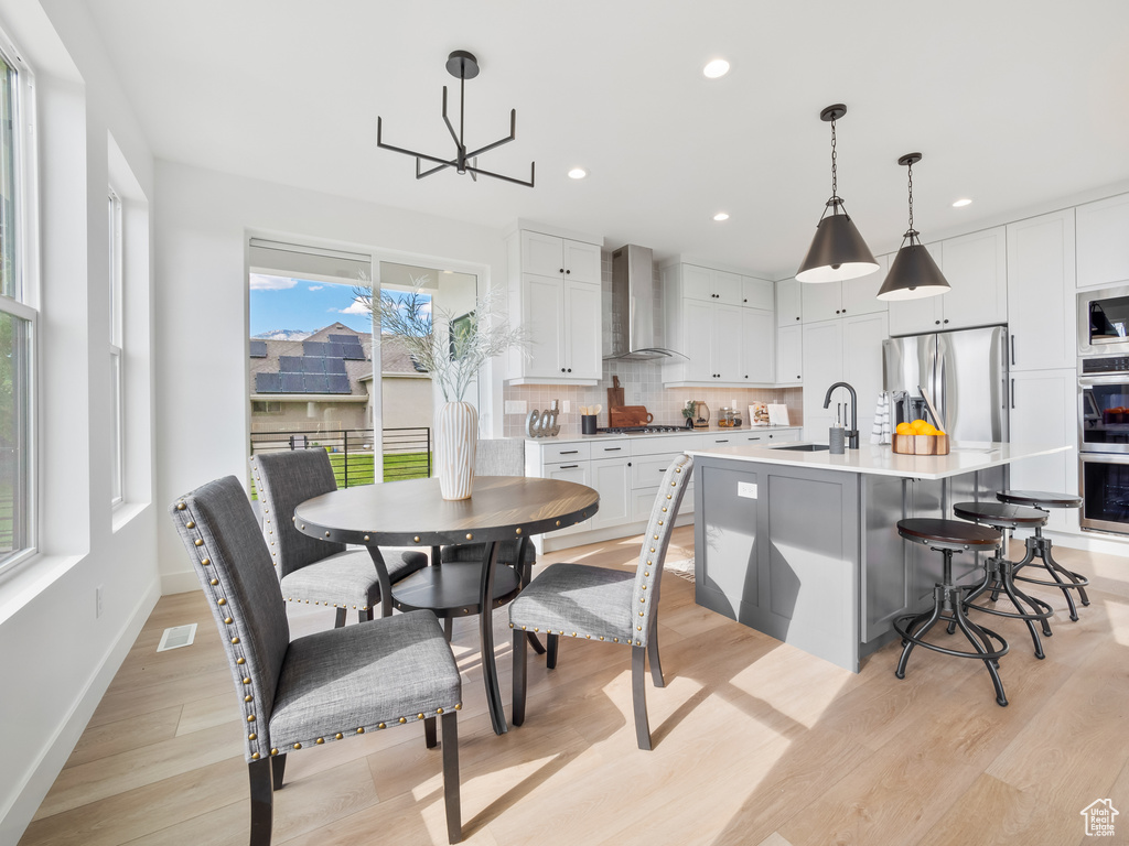 Dining room with sink, light hardwood / wood-style flooring, and a chandelier