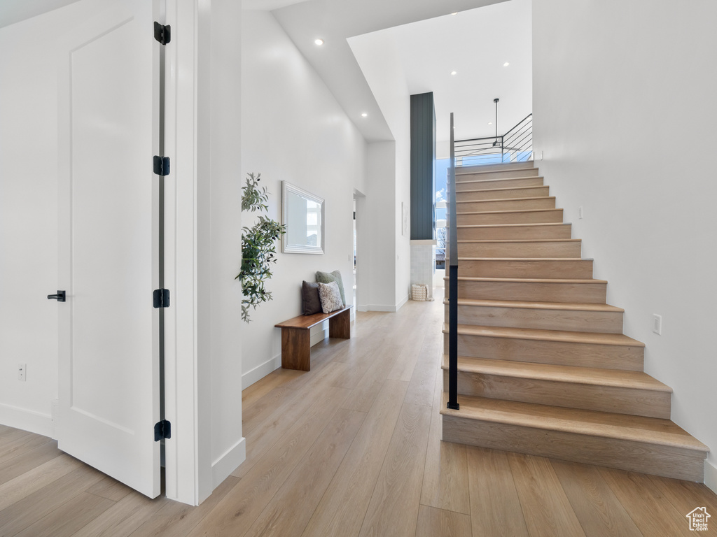 Stairway featuring a towering ceiling and wood-type flooring