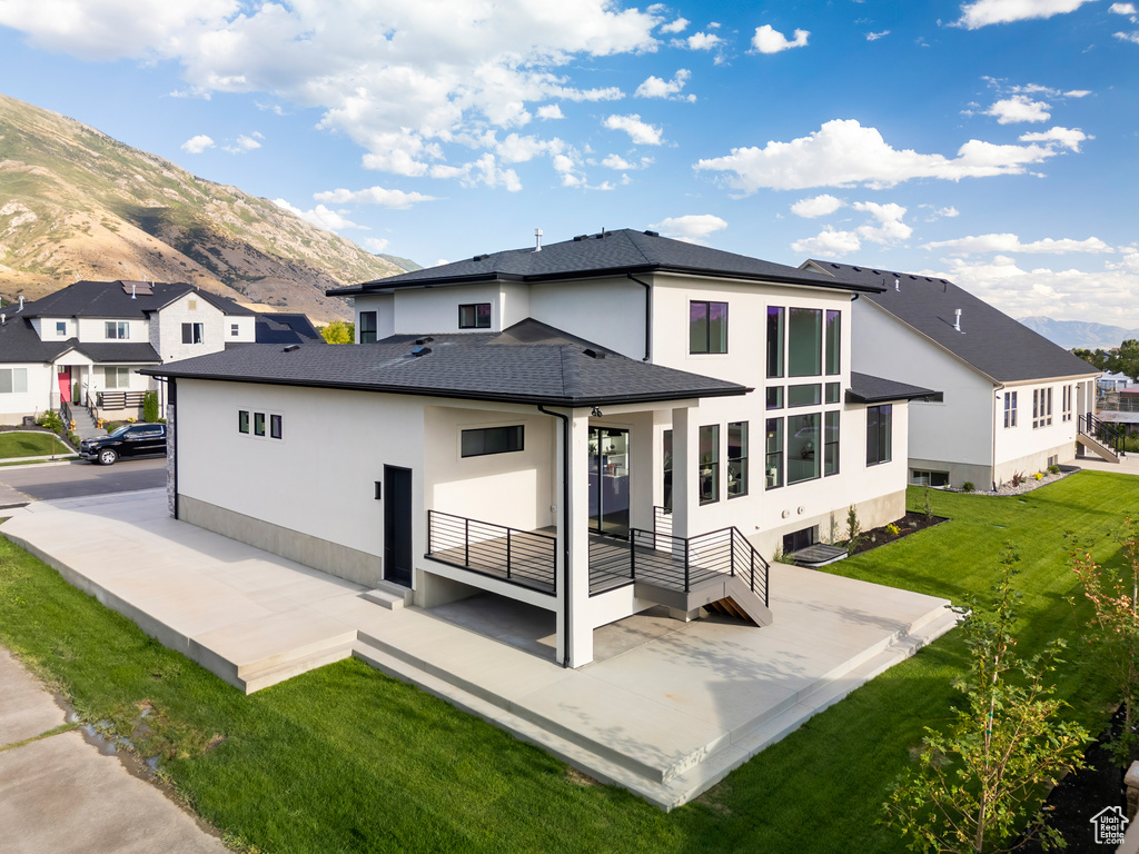 Back of house with a mountain view, a patio, and a yard