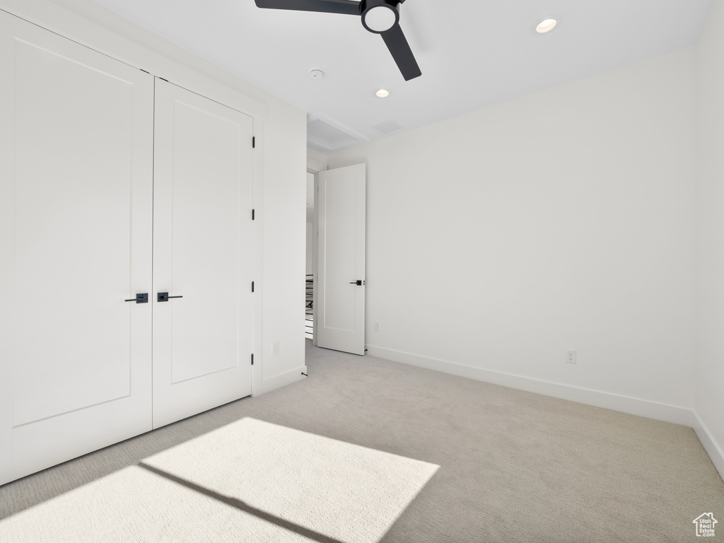 Unfurnished bedroom with ceiling fan, a closet, and light colored carpet