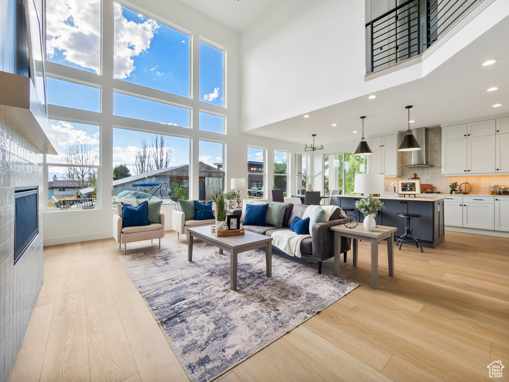 Living room with light wood-type flooring, a high ceiling, an inviting chandelier, and a fireplace