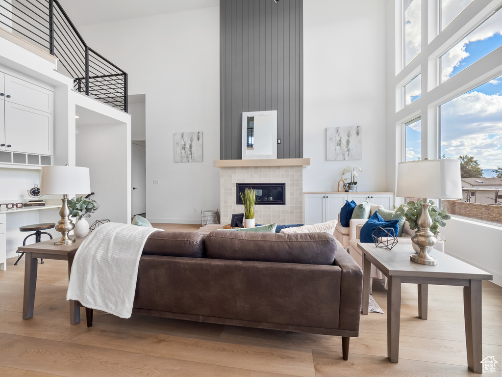 Living room featuring a high ceiling, light hardwood / wood-style floors, and a tile fireplace