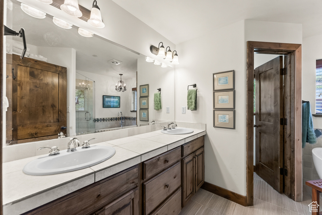 Bathroom featuring tile floors, a wealth of natural light, large vanity, and dual sinks