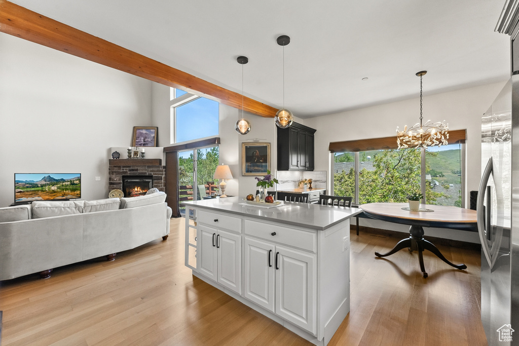 Kitchen with a stone fireplace, a healthy amount of sunlight, pendant lighting, and light hardwood / wood-style flooring