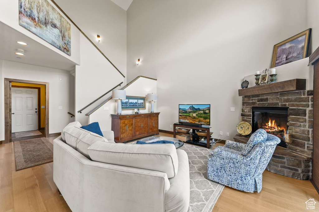 Living room with a towering ceiling, a fireplace, and light wood-type flooring