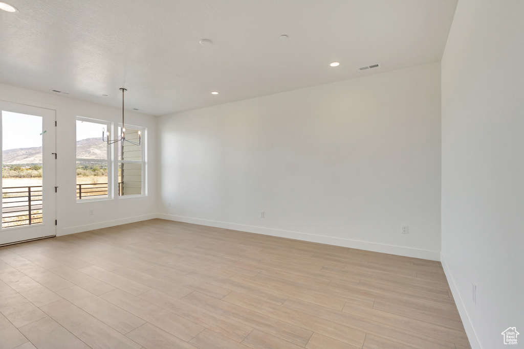 Unfurnished room with a chandelier and light wood-type flooring