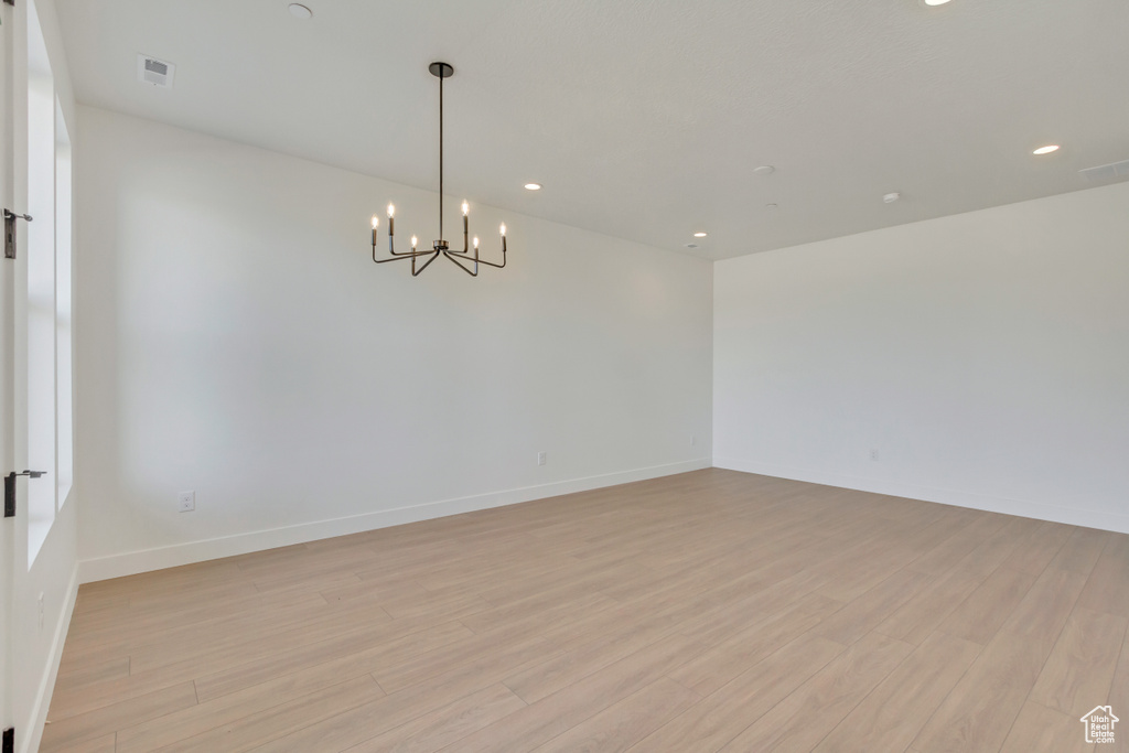 Spare room with light hardwood / wood-style flooring and a notable chandelier