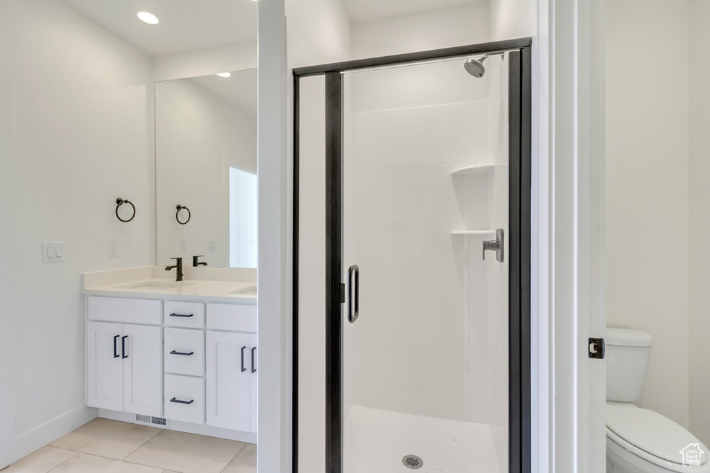 Bathroom featuring toilet, a shower with shower door, and vanity