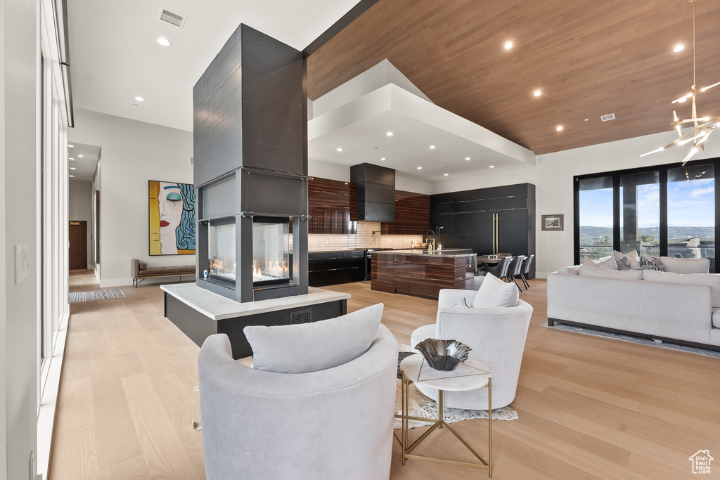 Living room with an inviting chandelier, a multi sided fireplace, and light hardwood / wood-style floors