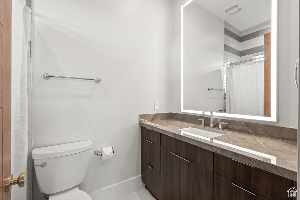 Bathroom featuring vanity, tile patterned flooring, and toilet