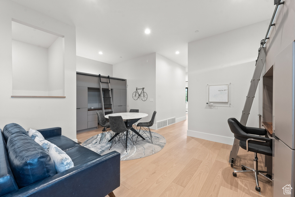 Living room with a barn door and light wood-type flooring