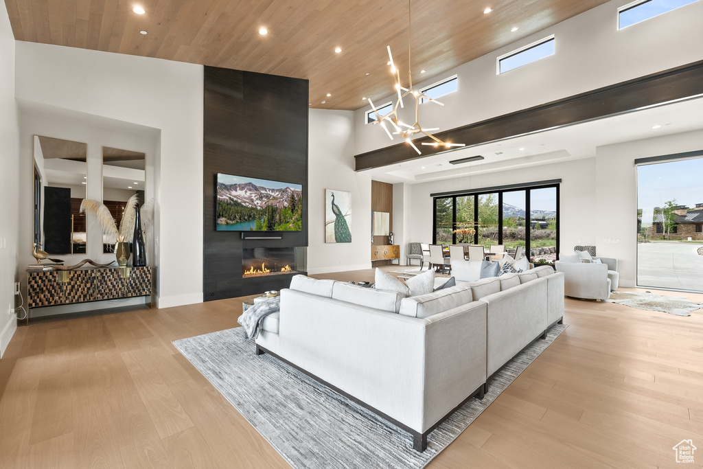 Living room with wooden ceiling, a towering ceiling, light hardwood / wood-style flooring, and an inviting chandelier