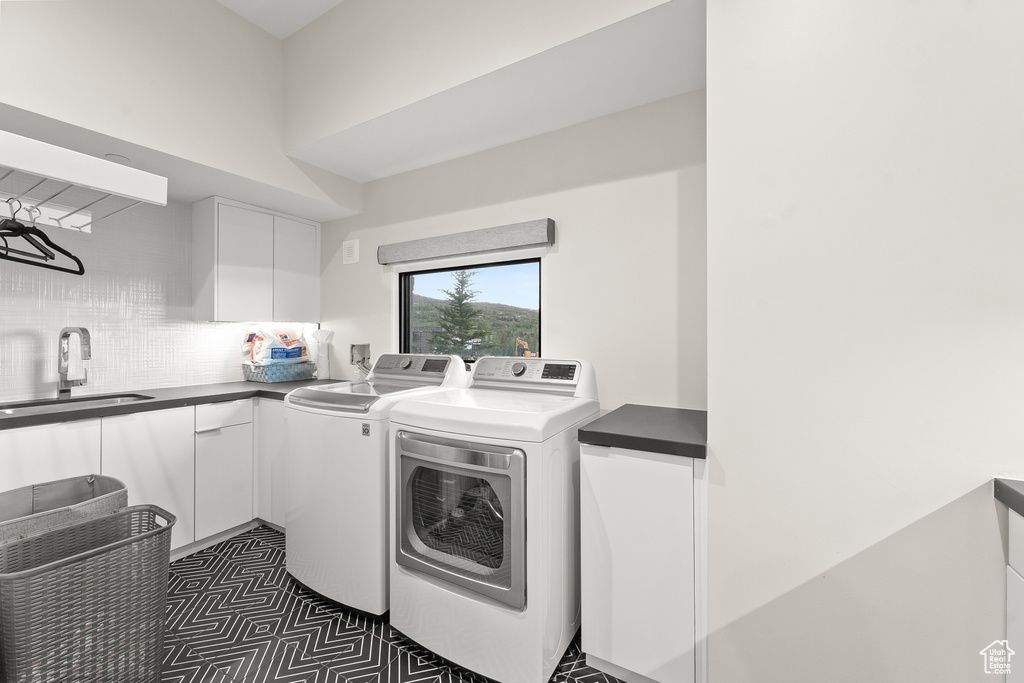 Clothes washing area featuring dark tile patterned flooring, separate washer and dryer, sink, and cabinets