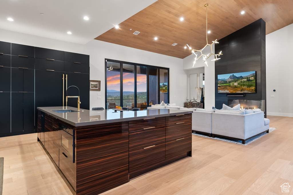 Kitchen featuring a large island, pendant lighting, a notable chandelier, light wood-type flooring, and sink