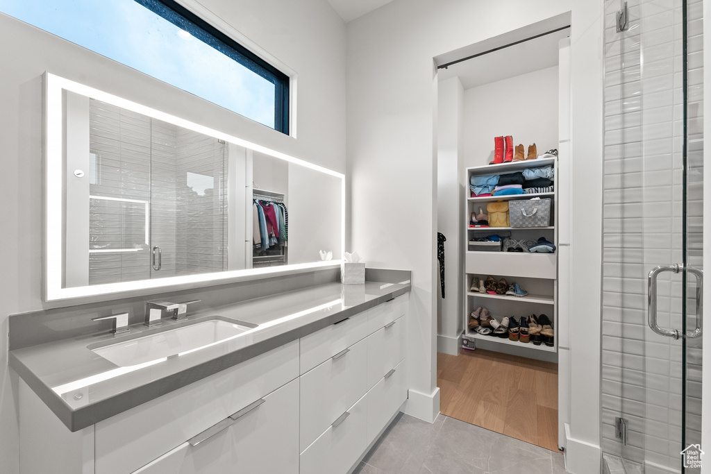 Bathroom featuring wood-type flooring, vanity, and walk in shower