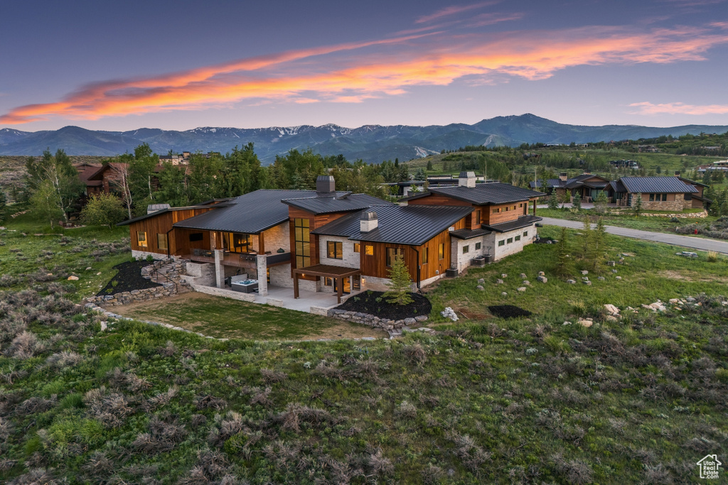 Back house at dusk with a patio, a mountain view, and a yard