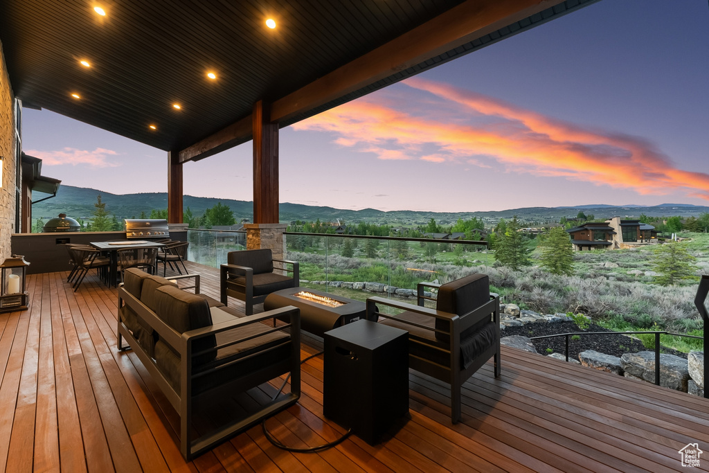 Deck at dusk featuring an outdoor hangout area, a mountain view, and area for grilling