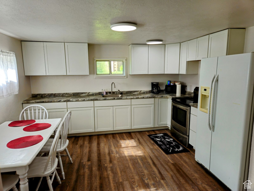 Kitchen featuring white fridge with ice dispenser, white cabinetry, dark hardwood / wood-style floors, and stainless steel electric range