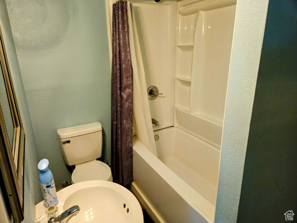 Full bathroom with sink, shower / bath combination with curtain, and toilet