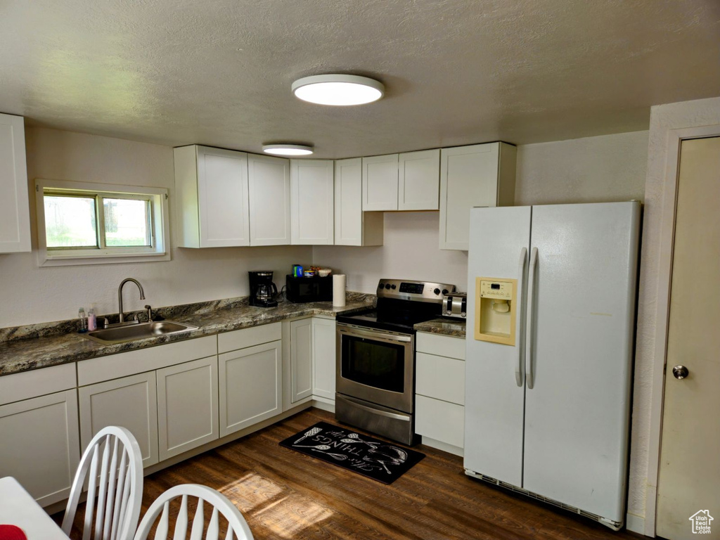 Kitchen with white cabinetry, white fridge with ice dispenser, dark hardwood / wood-style floors, sink, and stainless steel electric range