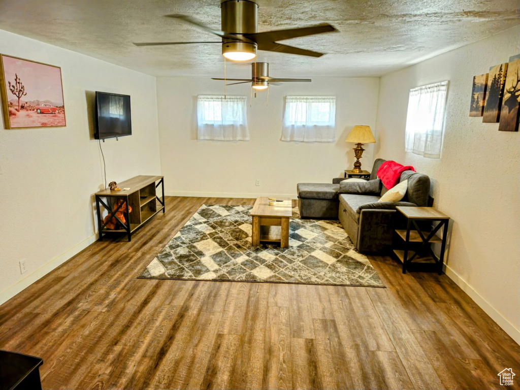 Living room featuring a textured ceiling, ceiling fan, and hardwood / wood-style floors