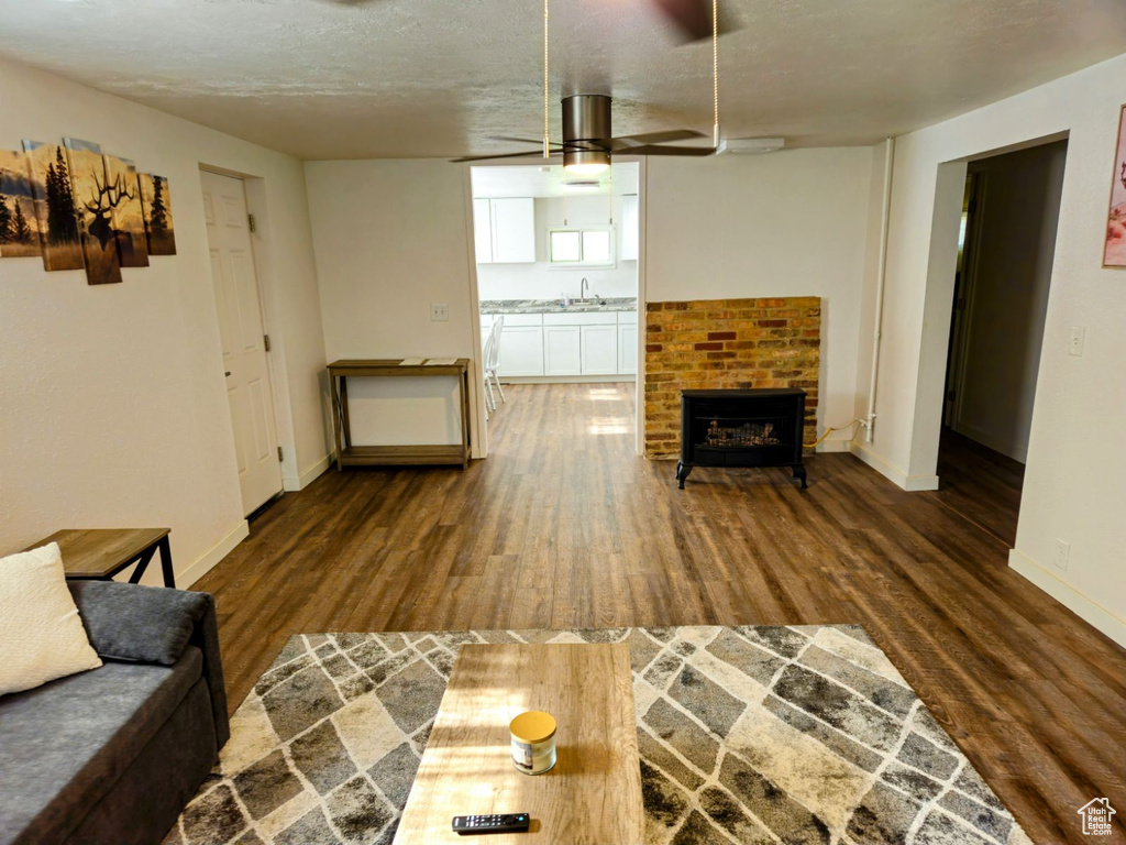 Living room with sink, a fireplace, ceiling fan, and dark hardwood / wood-style flooring