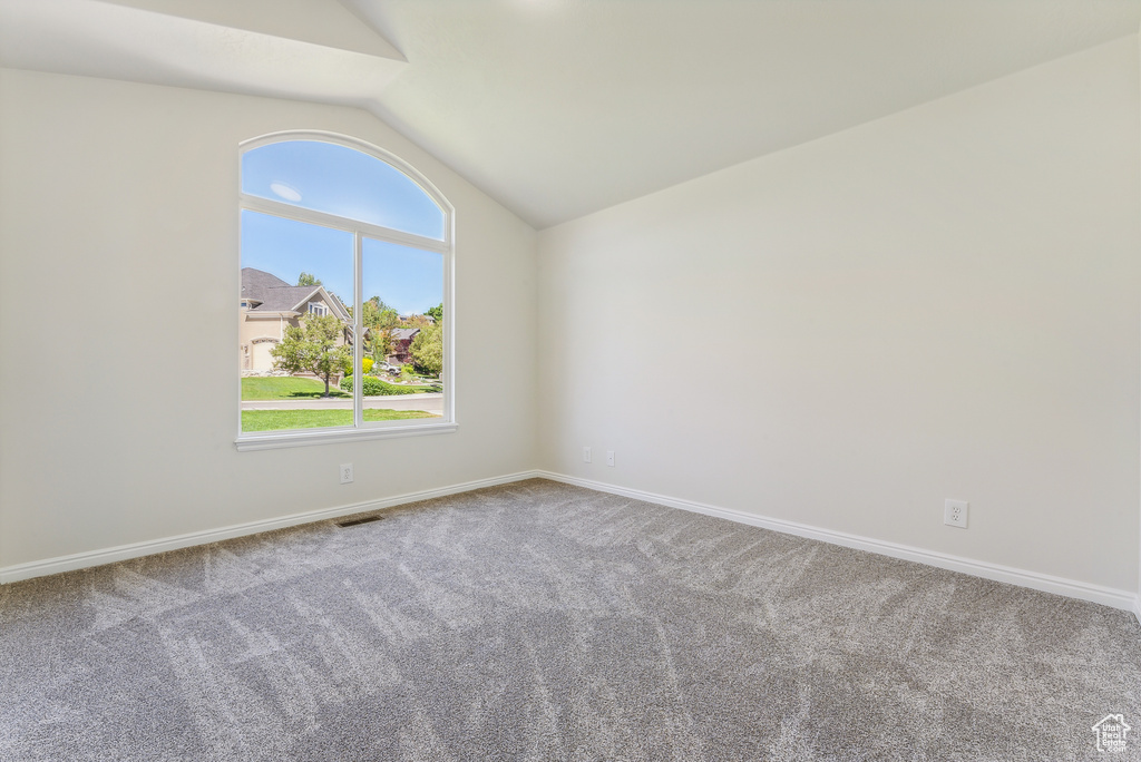 Carpeted spare room with lofted ceiling