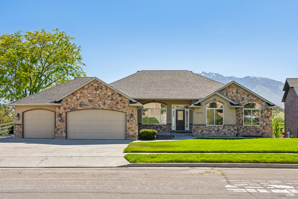 View of front of property with a front yard, a garage, and a mountain view