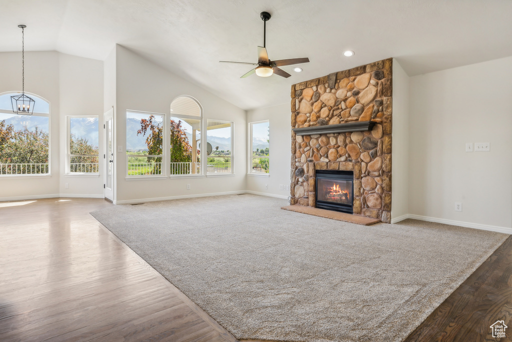 Unfurnished living room with high vaulted ceiling, a fireplace, carpet floors, and ceiling fan