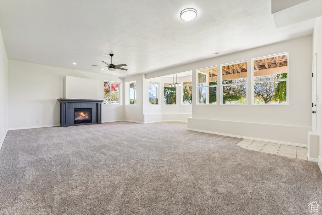 Unfurnished living room with carpet flooring, ceiling fan, and a fireplace