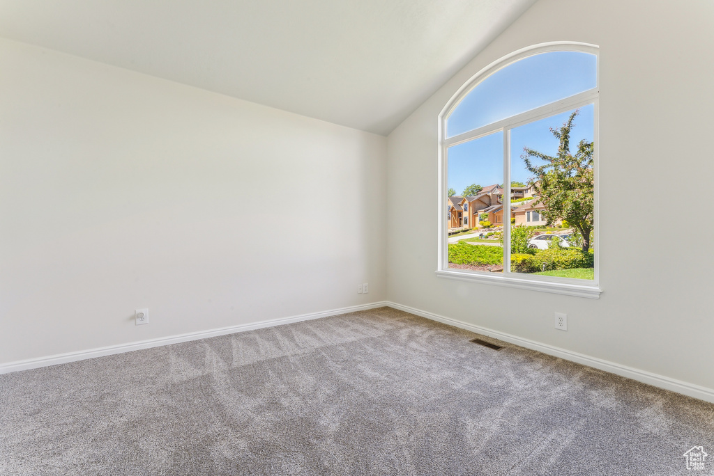 Spare room featuring vaulted ceiling and carpet floors