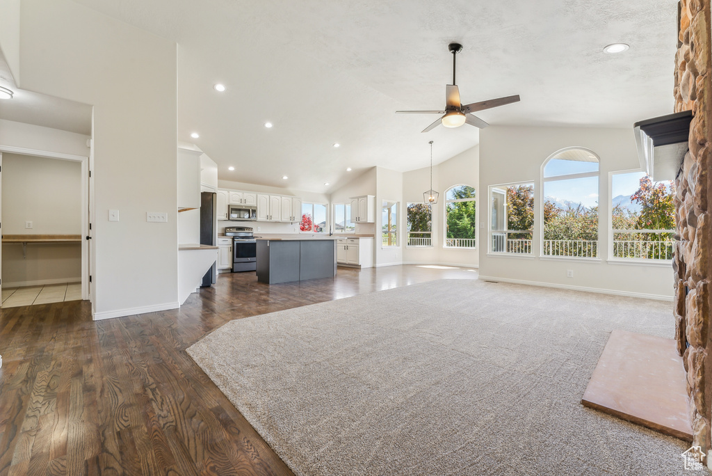 Living room featuring high vaulted ceiling, dark wood-type flooring, and ceiling fan