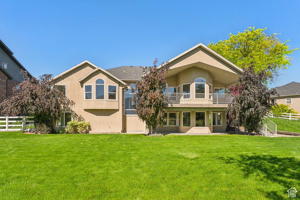 Back of property with a patio, a balcony, and a lawn