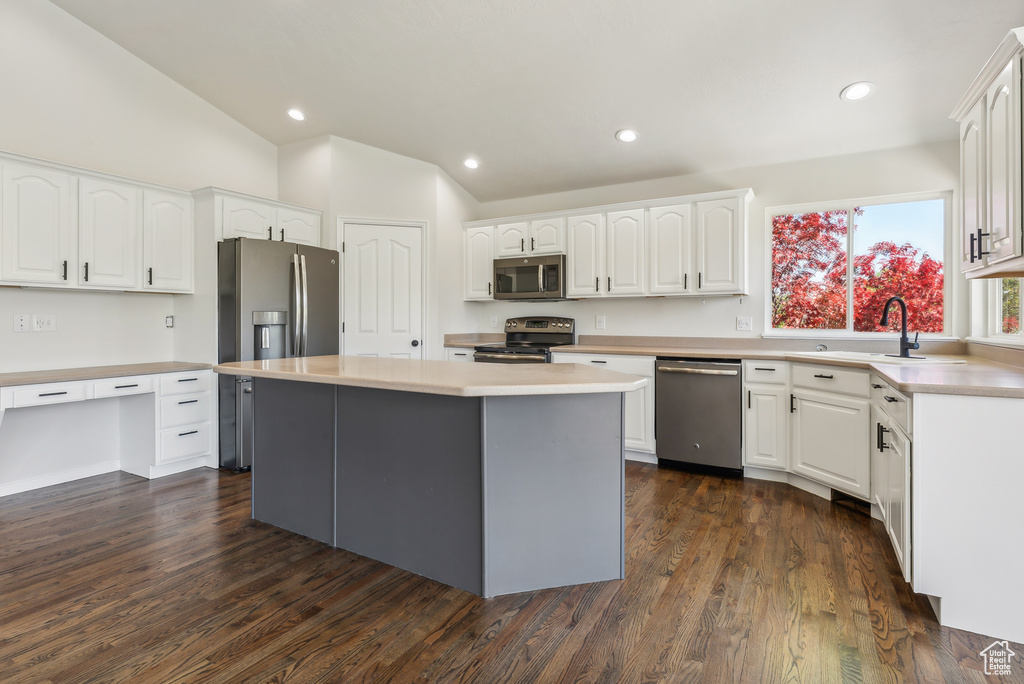 Kitchen featuring white cabinets, vaulted ceiling, appliances with stainless steel finishes, and a center island