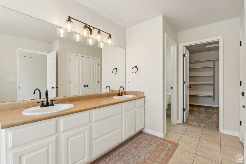 Bathroom featuring tile flooring, toilet, and double sink vanity