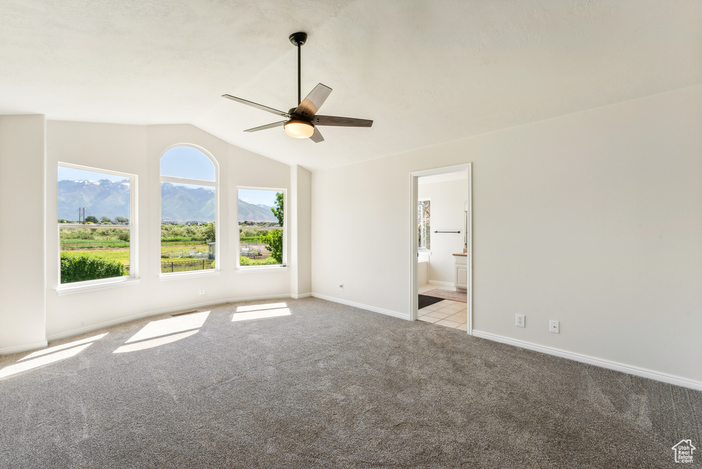 Spare room featuring light colored carpet, ceiling fan, and lofted ceiling