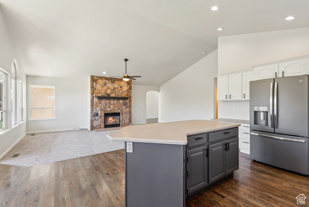 Kitchen with stainless steel fridge with ice dispenser, a fireplace, ceiling fan, white cabinetry, and lofted ceiling