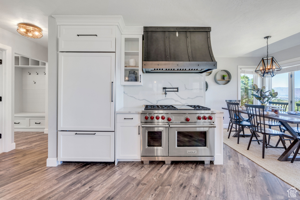 Kitchen with range hood, hanging light fixtures, range with two ovens, dark hardwood / wood-style floors, and a notable chandelier