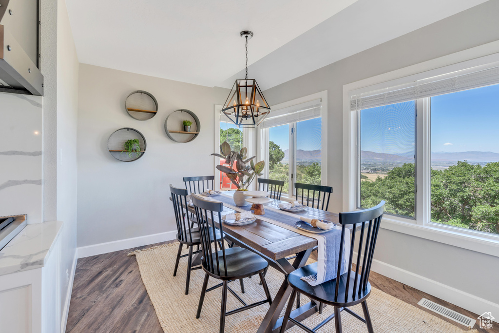 Dining room with a notable chandelier and dark wood-type flooring